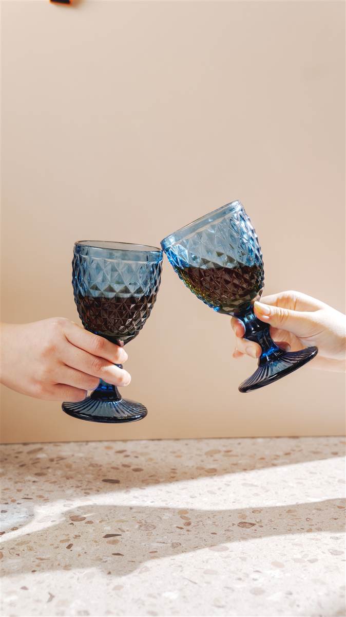 Two blue cut-glass goblets in warm light, Red Ribbon